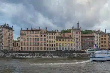 a boat traveling down a river next to tall buildings